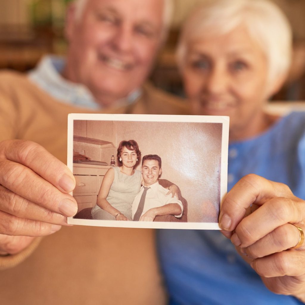 Older couple holding a picture of themselves.