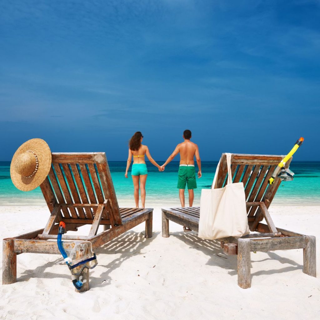 Couple holding hands on the beach.