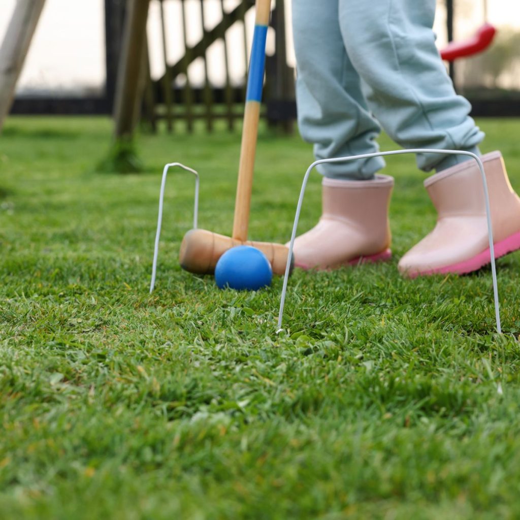 Little kid playing croquet.