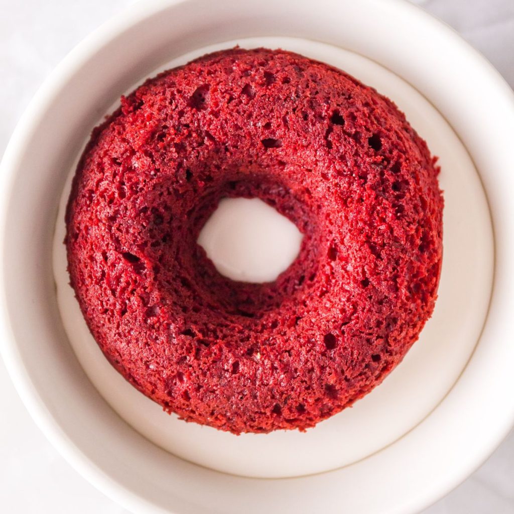 Red donut in a bowl of frosting.