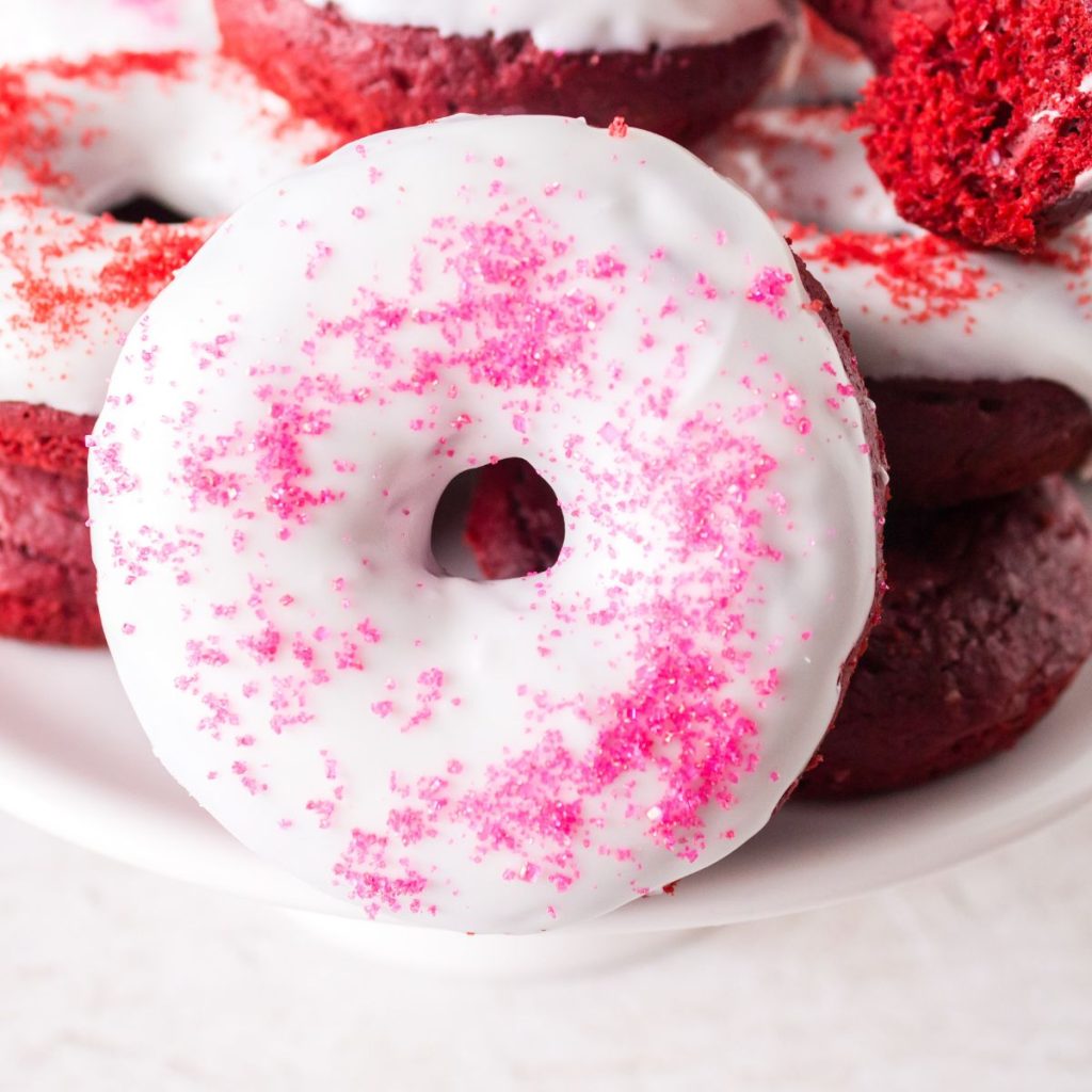 Donut with white icing and pink sprinkles. 