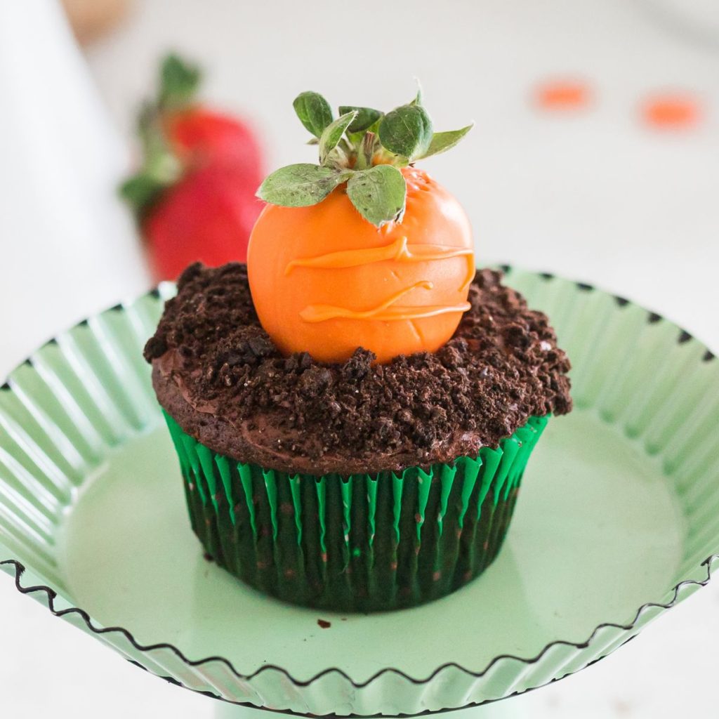 Chocolate cupcake with orange covered strawberry.
