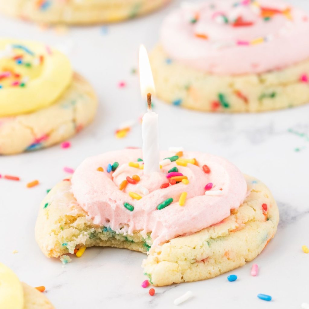 Cookie with pink frosting, sprinkles, and a candle.