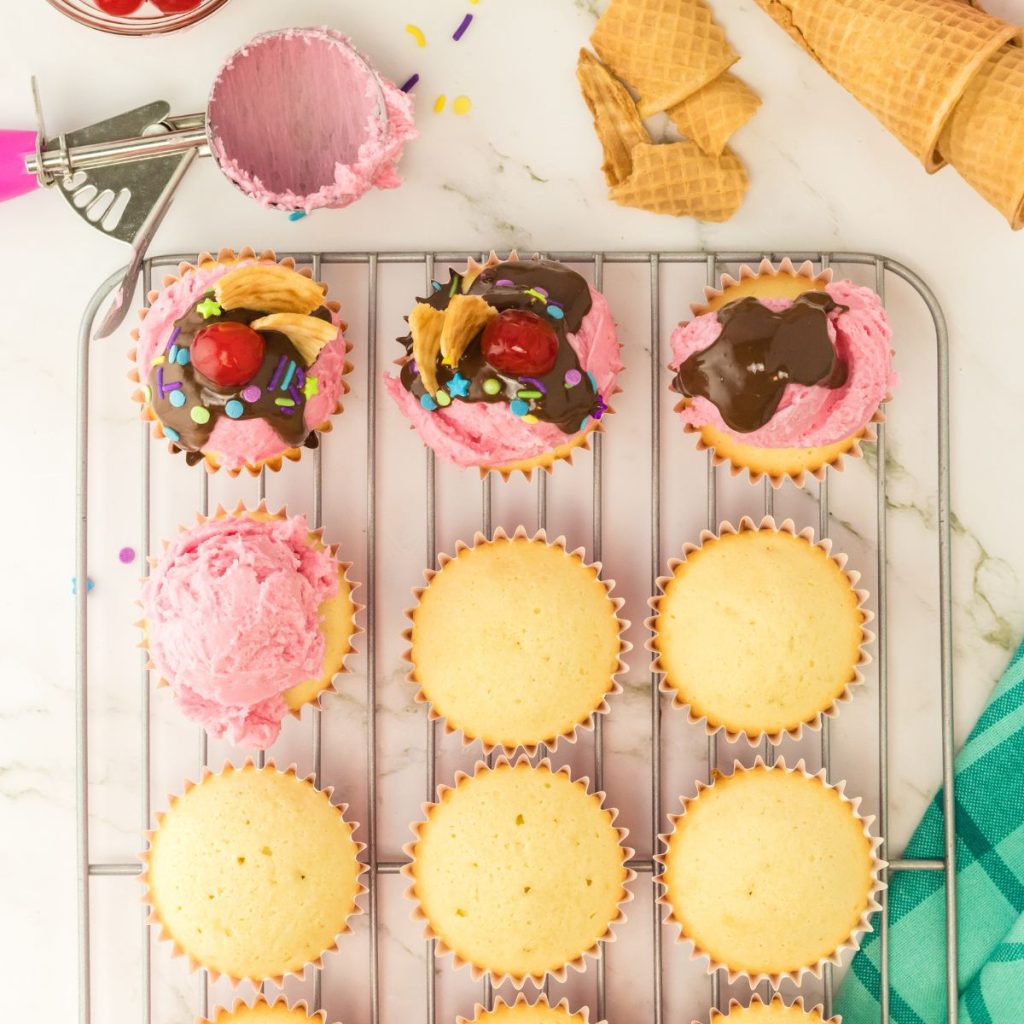 Vanilla cupcakes with pink frosting on a wire rack. 