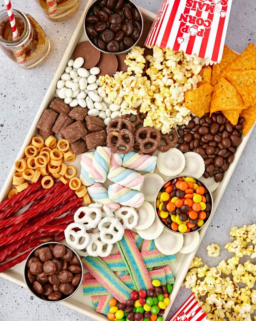 Tray with popcorn, candy, chocolate covered pretzels, and chips. 