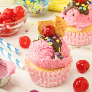 Sundae cupcakes topped with pink frosting and a cherry.