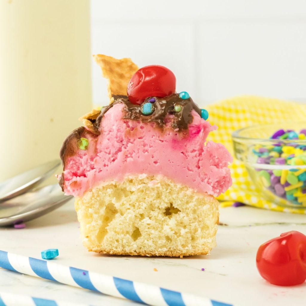 Vanilla cupcake with pink frosting cut in half. 