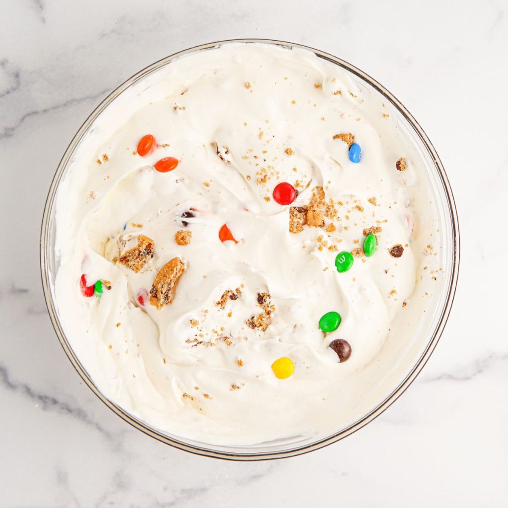 Bowl of whipped cream with candy and crushed cookies. 