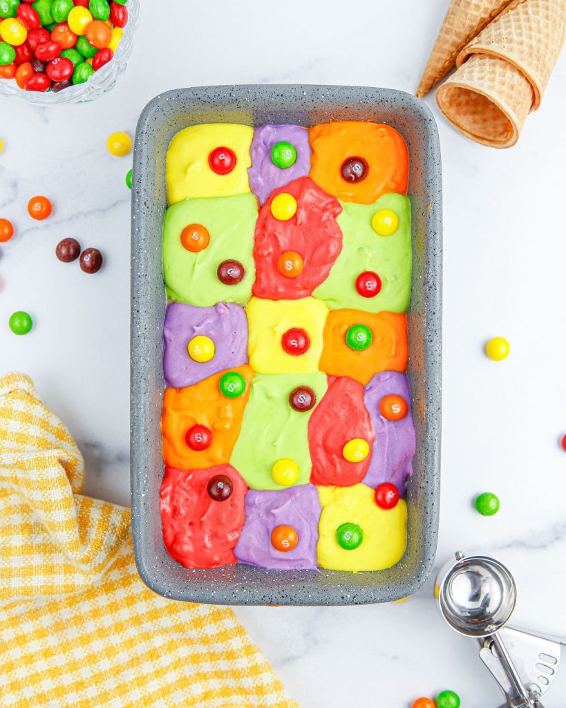 Loaf pan with colorful ice cream and skittles candy.