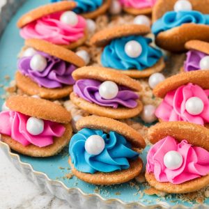 Cookies filled with blue, pink and purple frosting and a white candy.