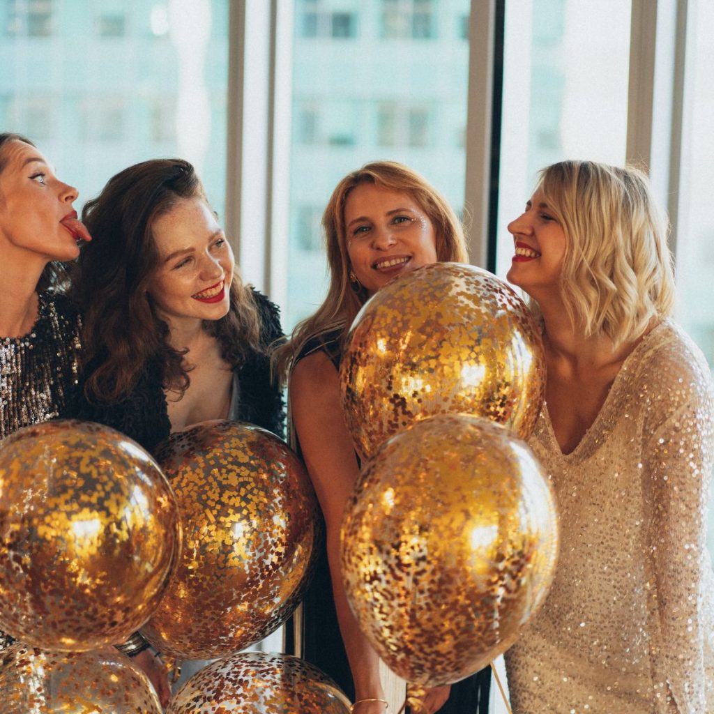 Women holding gold balloons.