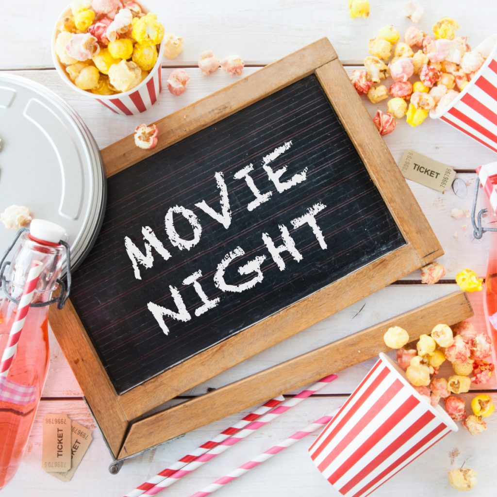 Sign with movie night, popcorn, and red straws. 