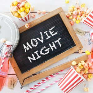 Sign with movie night, popcorn, and red straws.