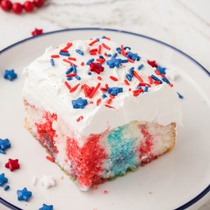 Piece of red white and blue poke cake on a plate.