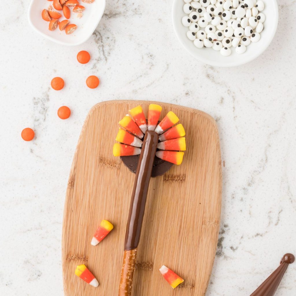 Pretzel rod covered in chocolate with candy corns.