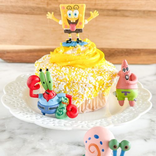Yellow cupcake topped with SpongeBob figure.