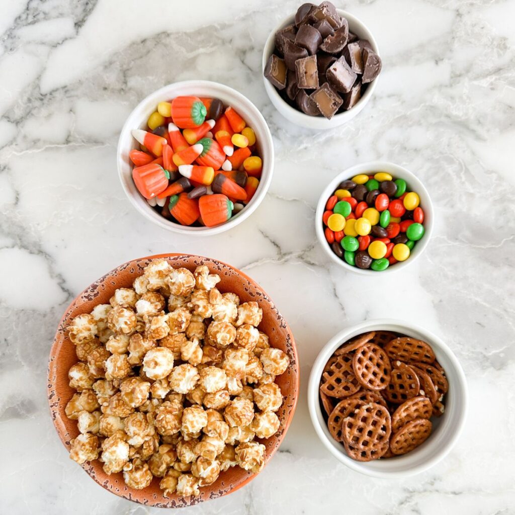 Bowl of caramel con, candy corn, pretzels, and chocolate candy. 