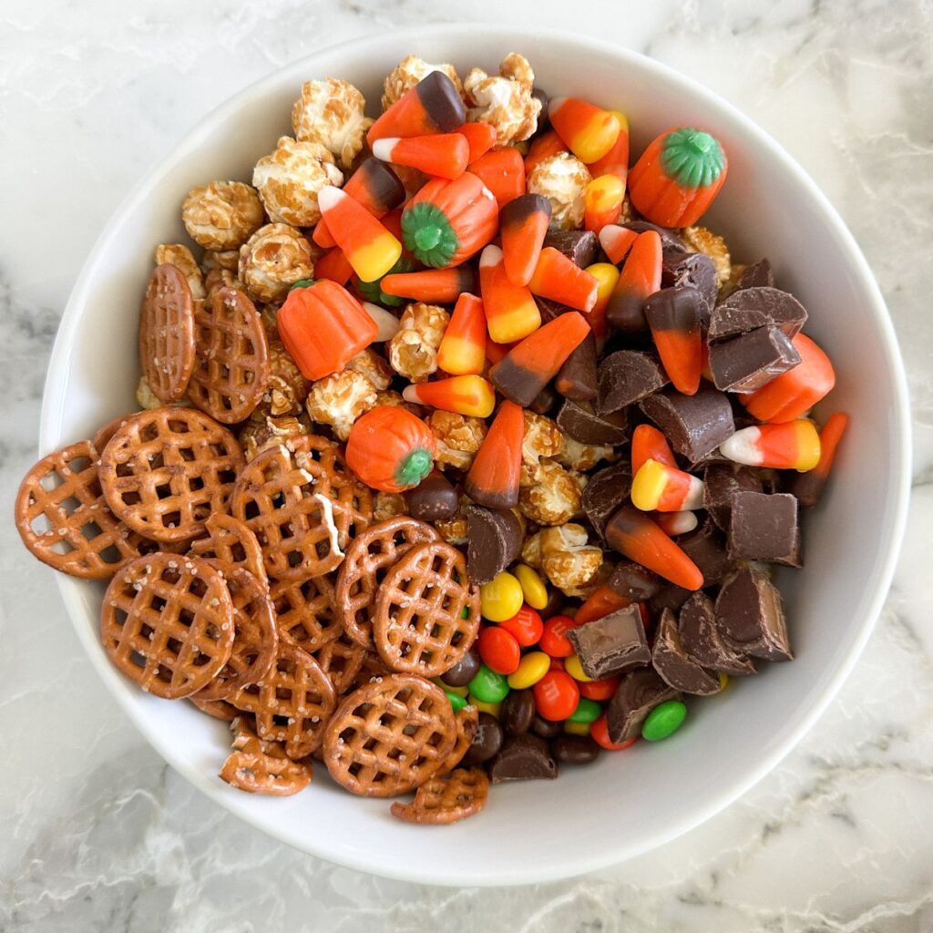 Large bowl with pretzels, caramel corn, candy corn, and rolos. 