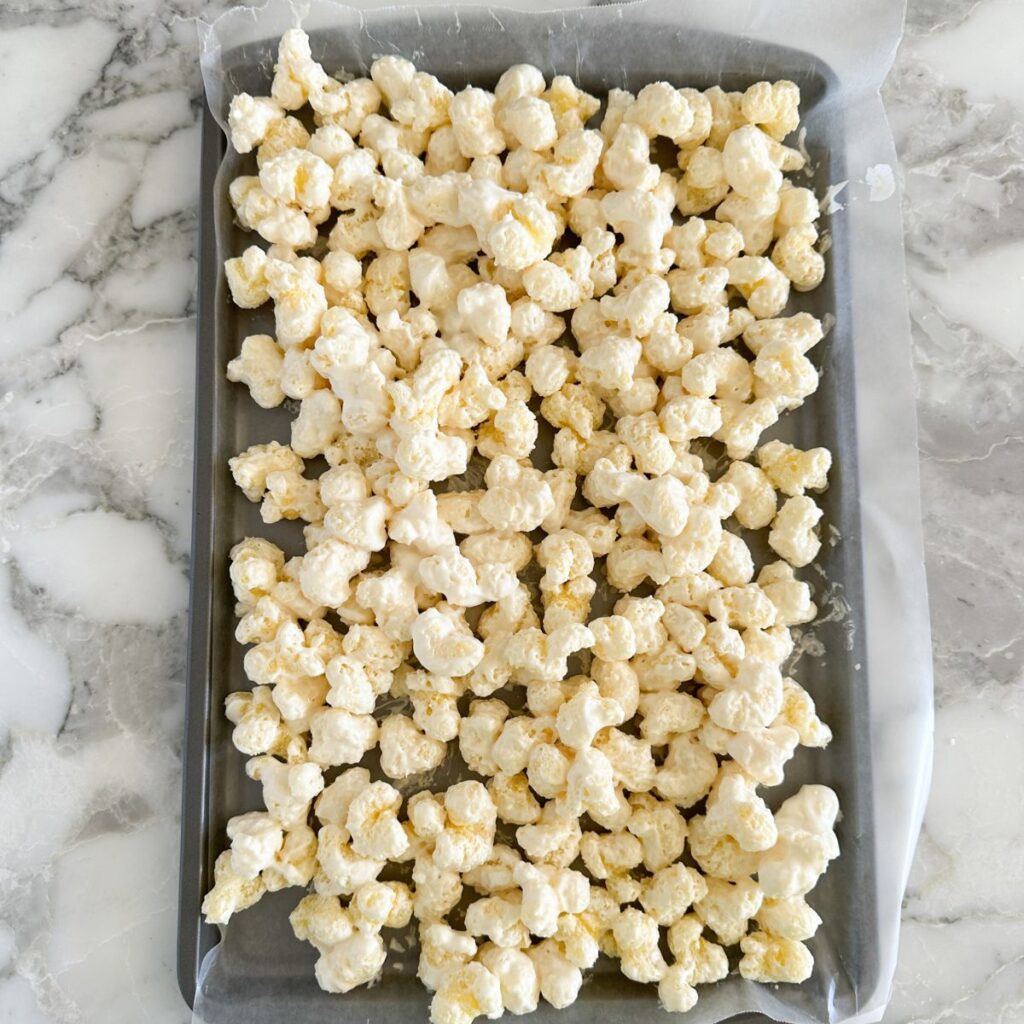 Baking sheet with white chocolate covered puffcorn. 