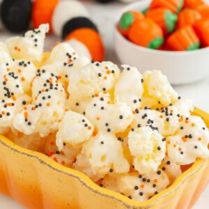 White chocolate covered puffcorn with orange and black sprinkles.