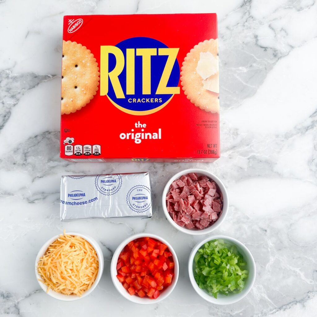 Box of Ritz crackers, cream cheese, salami, shredded cheese, red peppers, and green onions.