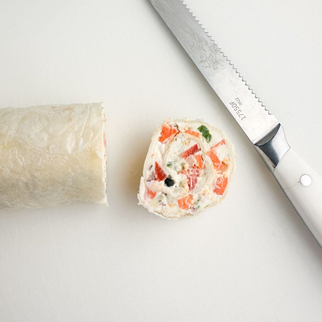 Tortilla roll up with a slice and a knife.