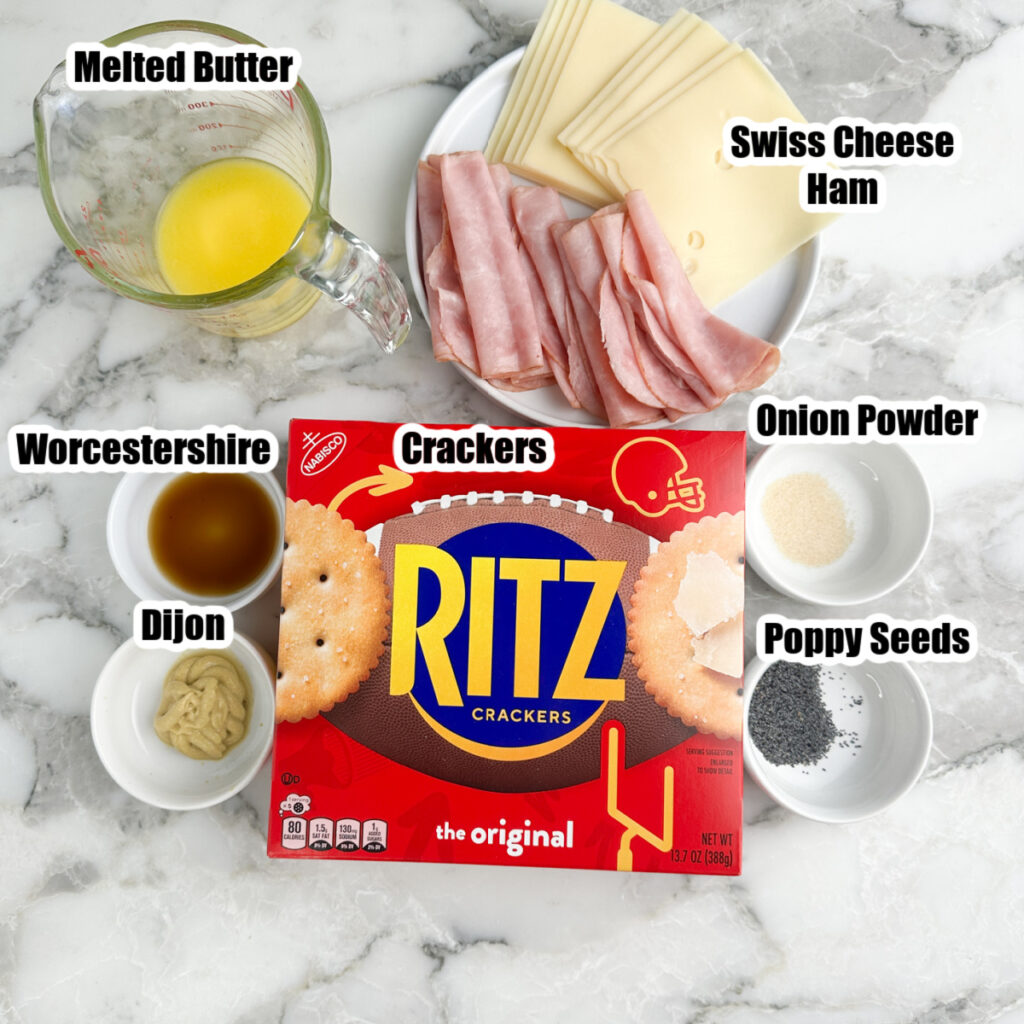 Box of Ritz crackers, plate of cheese and ham, bowls of butter, seasonings, Dijon, and Worcestershire.
