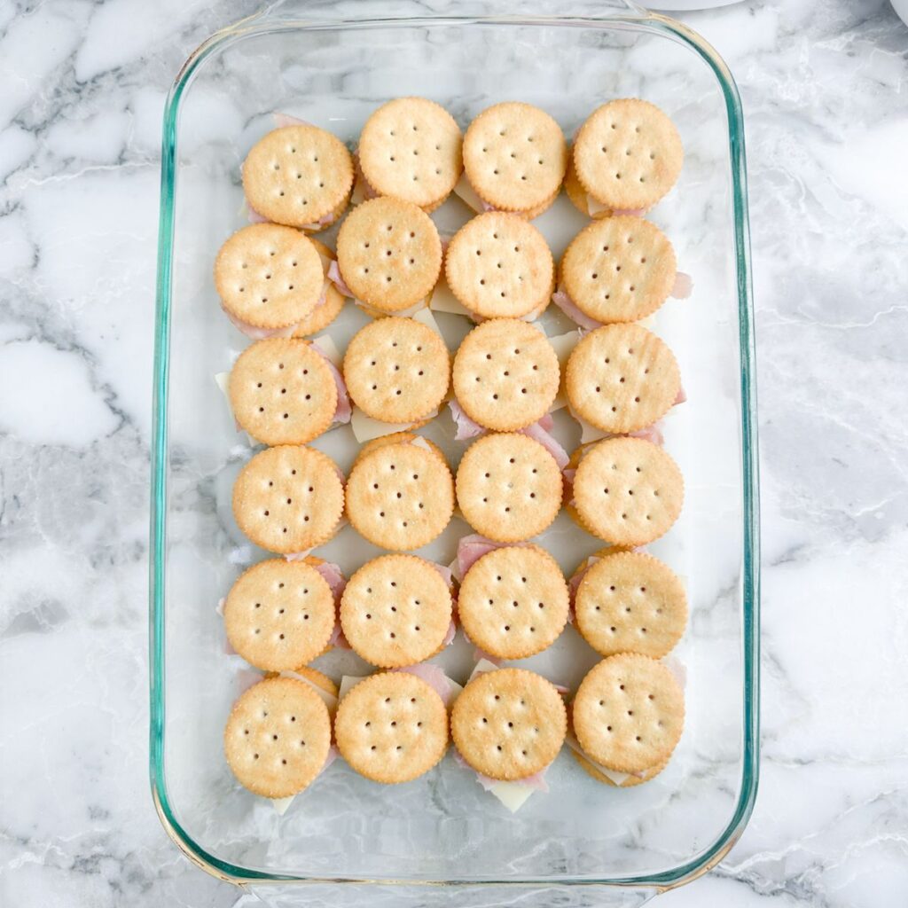 Baking dish with crackers, cheese, and ham, topped with crackers. 