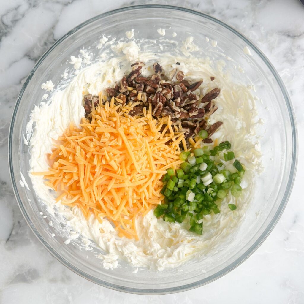 Bowl with cream cheese, shredded cheese, pecans, and green onions. 
