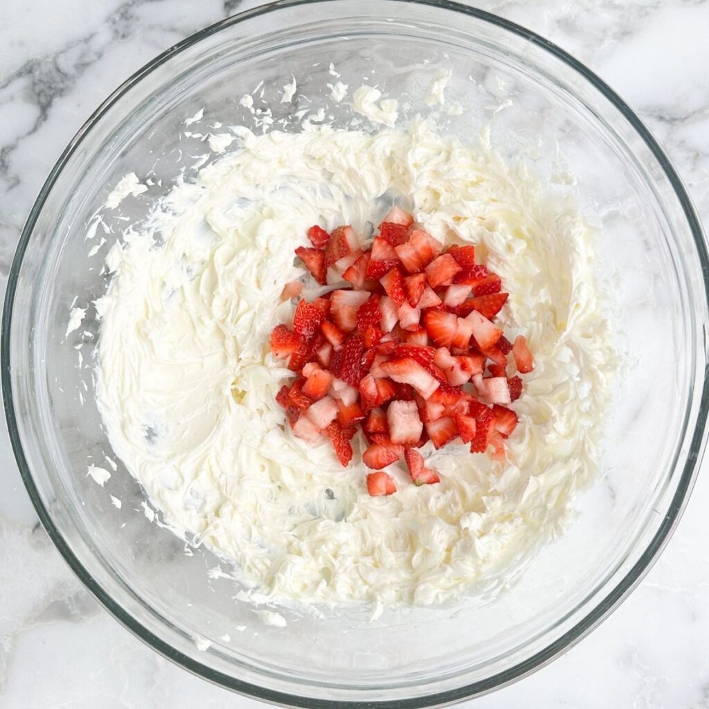Bowl with cream cheese and diced strawberries. 