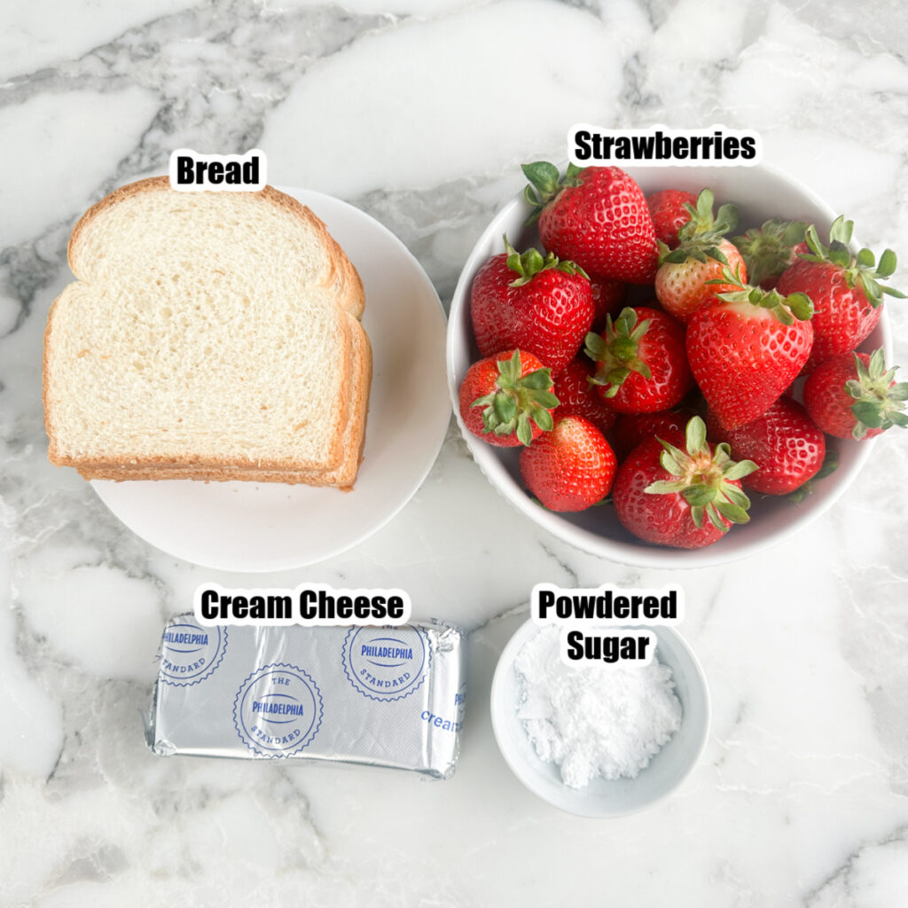 Bread, bowl of strawberries, cream cheese, bowl of powdered sugar. 