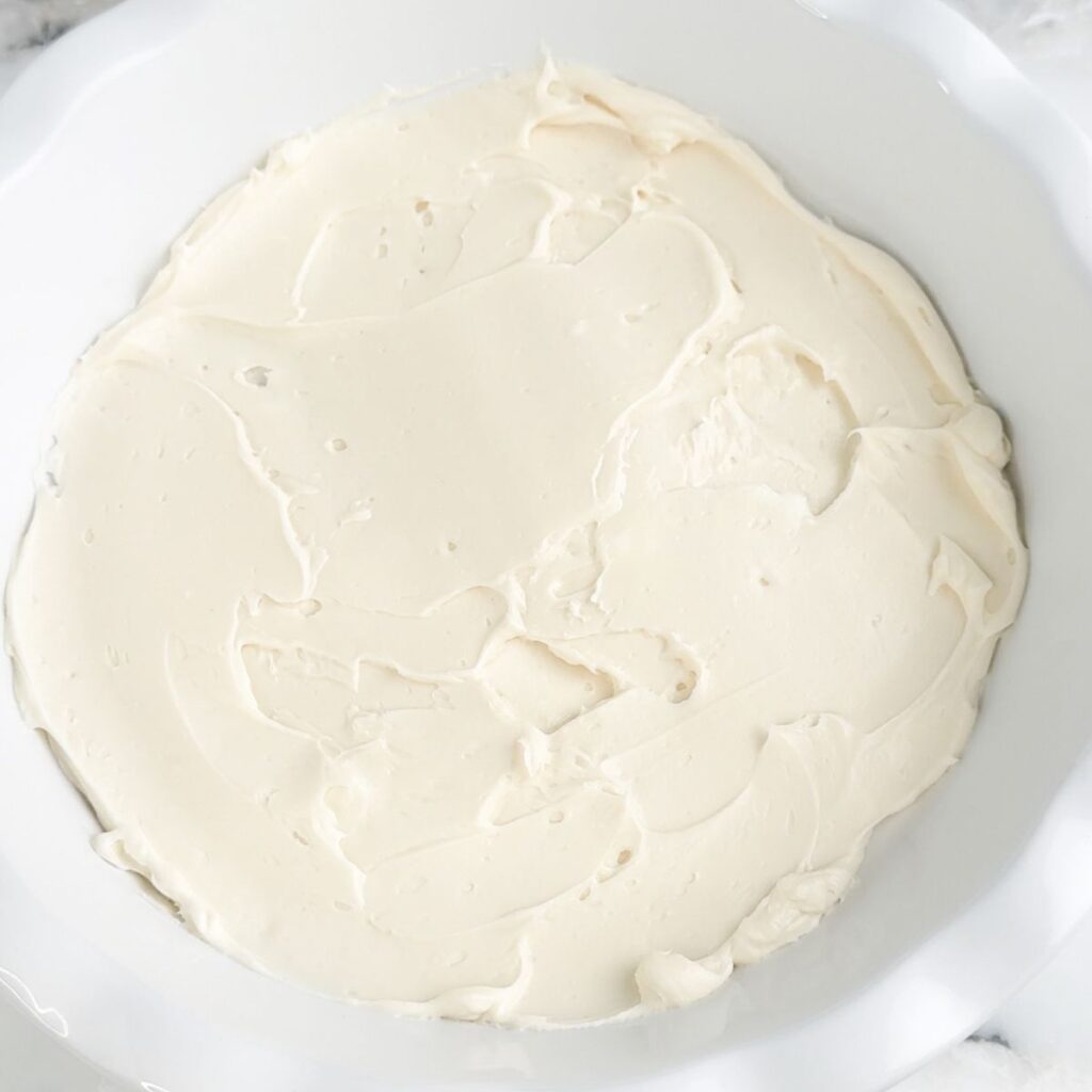 Pie dish with cream cheese mixture spread in the dish.